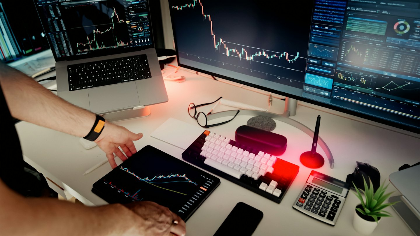 Hände bedienen ein Tablet mit Finanzdiagrammen in einem modernen Büro.